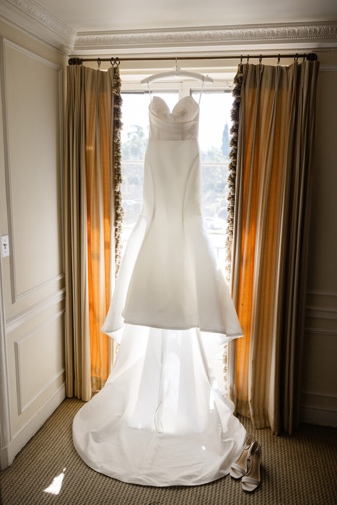 Kelly’s wedding dress hanging in the window light.