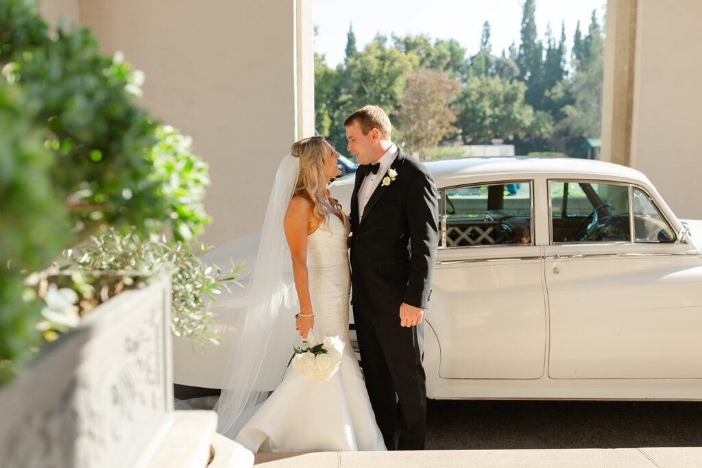 Ben and Kelly standing beside their classic wedding car.
