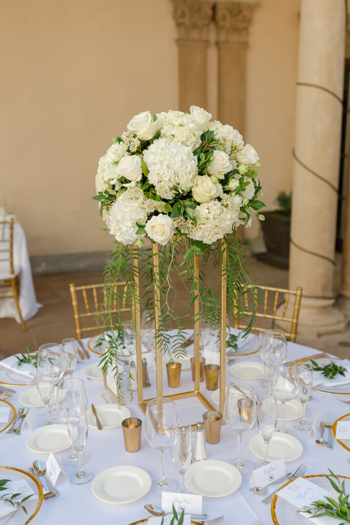 White bridal bouquet with greenery displayed on a gold chair.