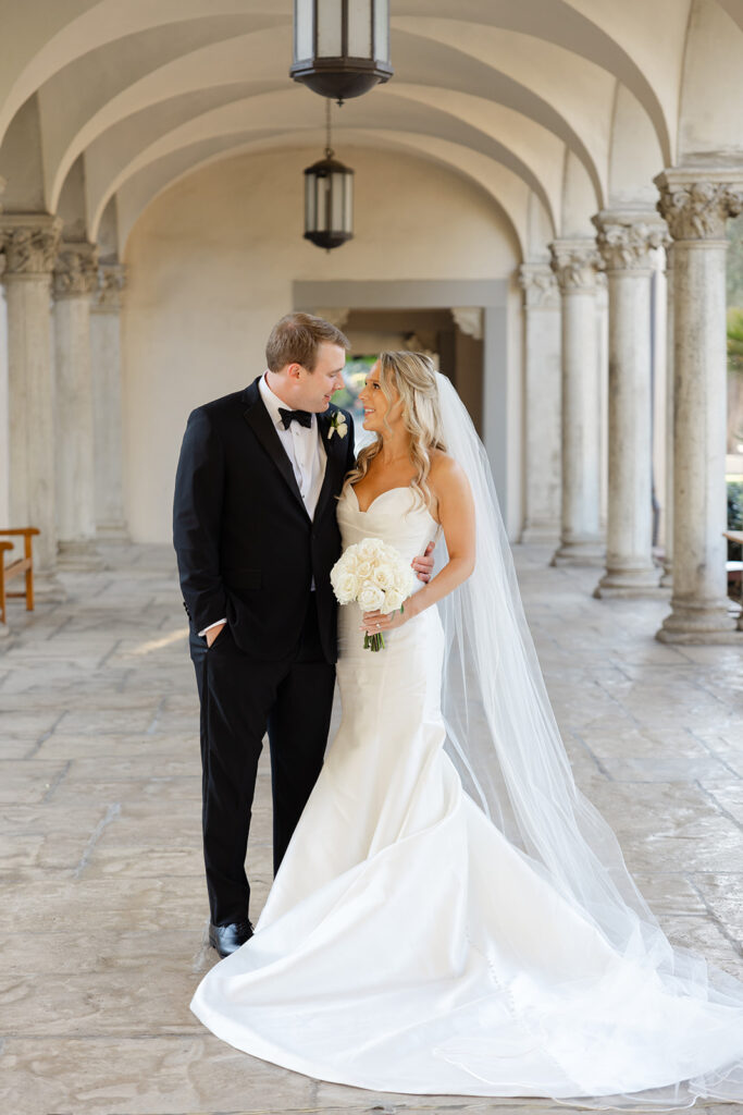 Ben leaning toward Kelly during portraits beneath the arches.