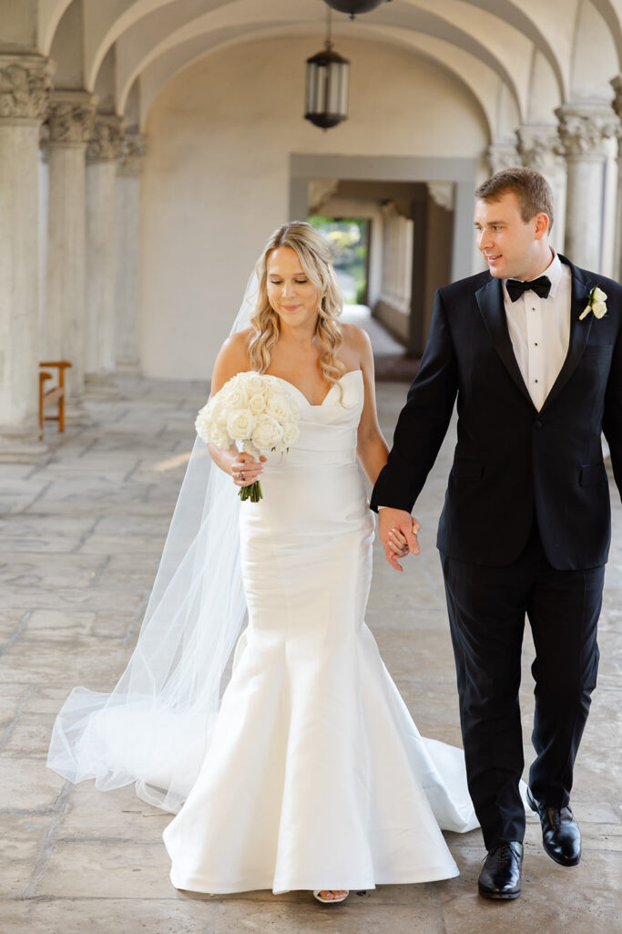 Kelly and Ben walking hand in hand through the Athenaeum colonnade.