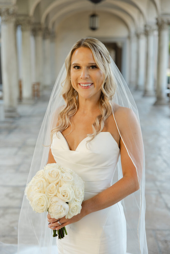 Kelly holding her white bridal bouquet with her veil framing her face.