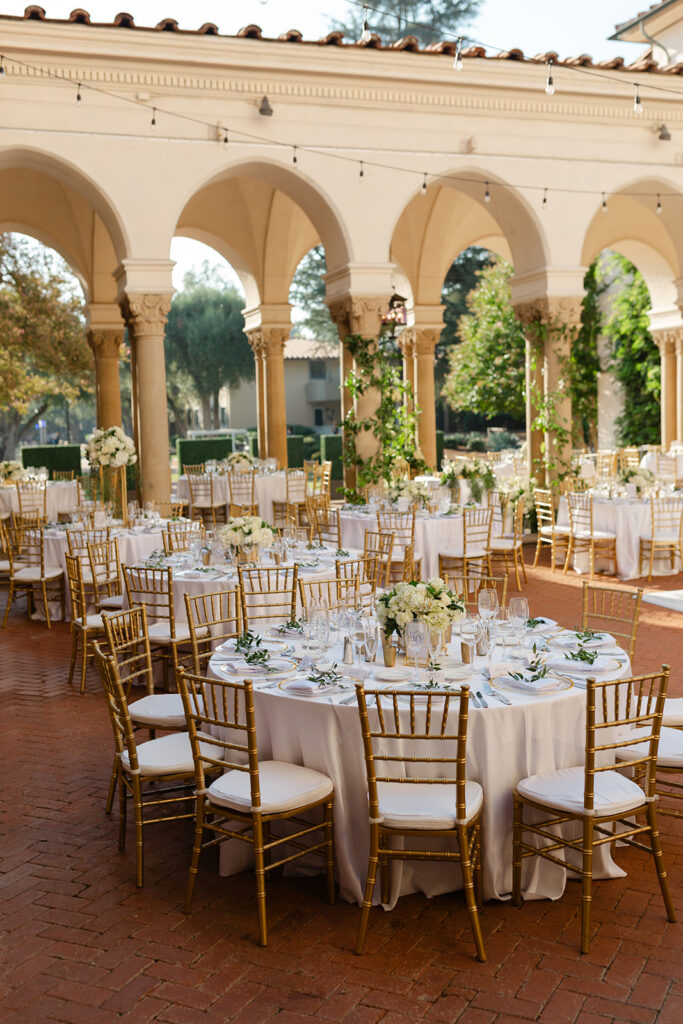 Round wedding reception tables beneath the Athenaeum’s arches.
