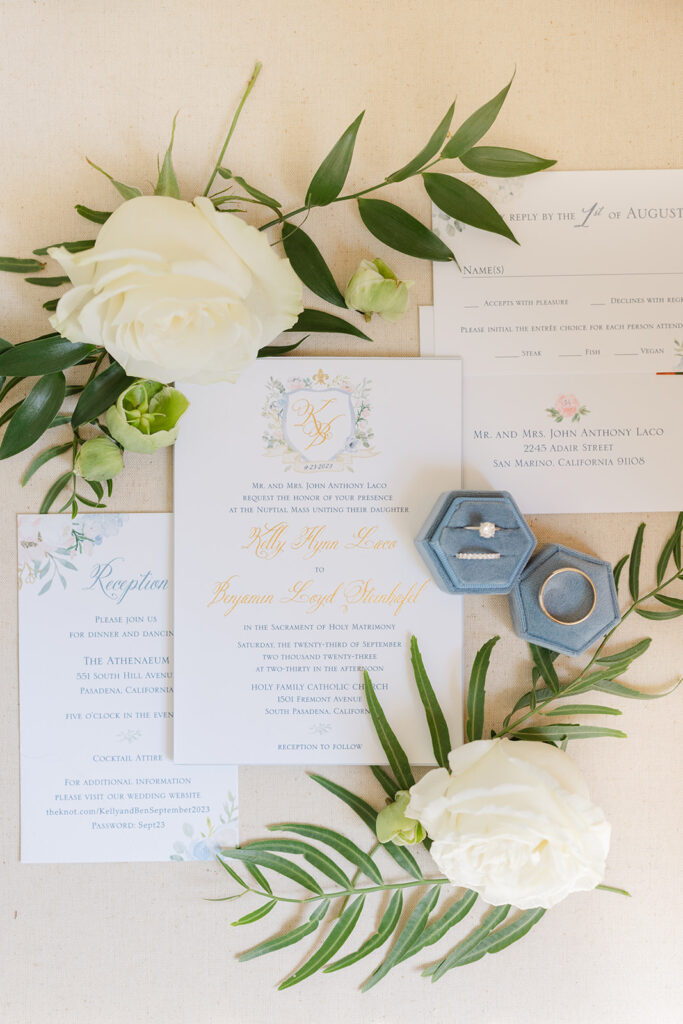 Wedding rings and white roses arranged on the invitation suite.