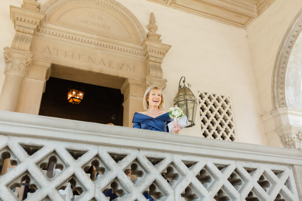 Kelly holding her bouquet on an ornate balcony.