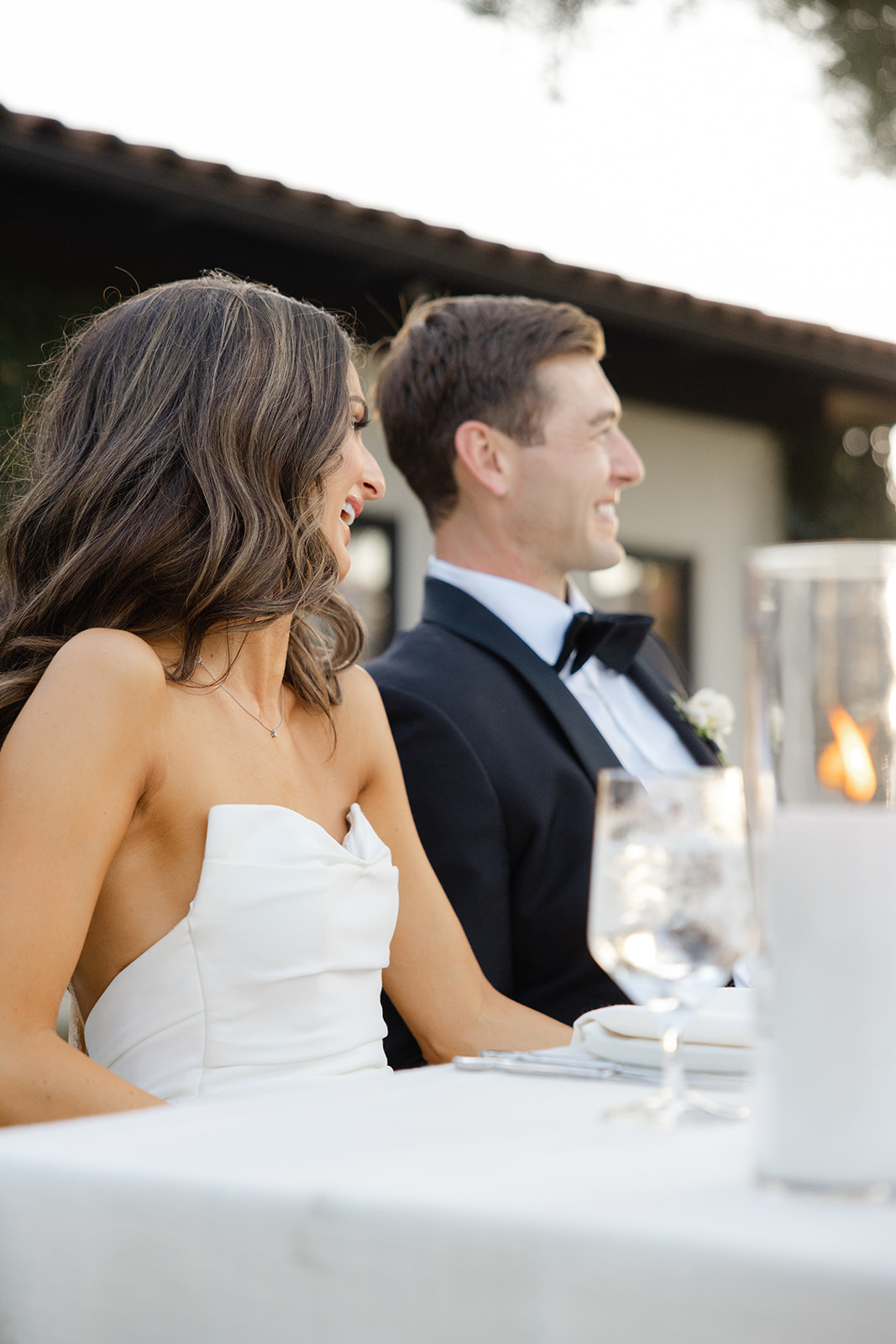 Jake smiling beside Zoe at their wedding reception table.
