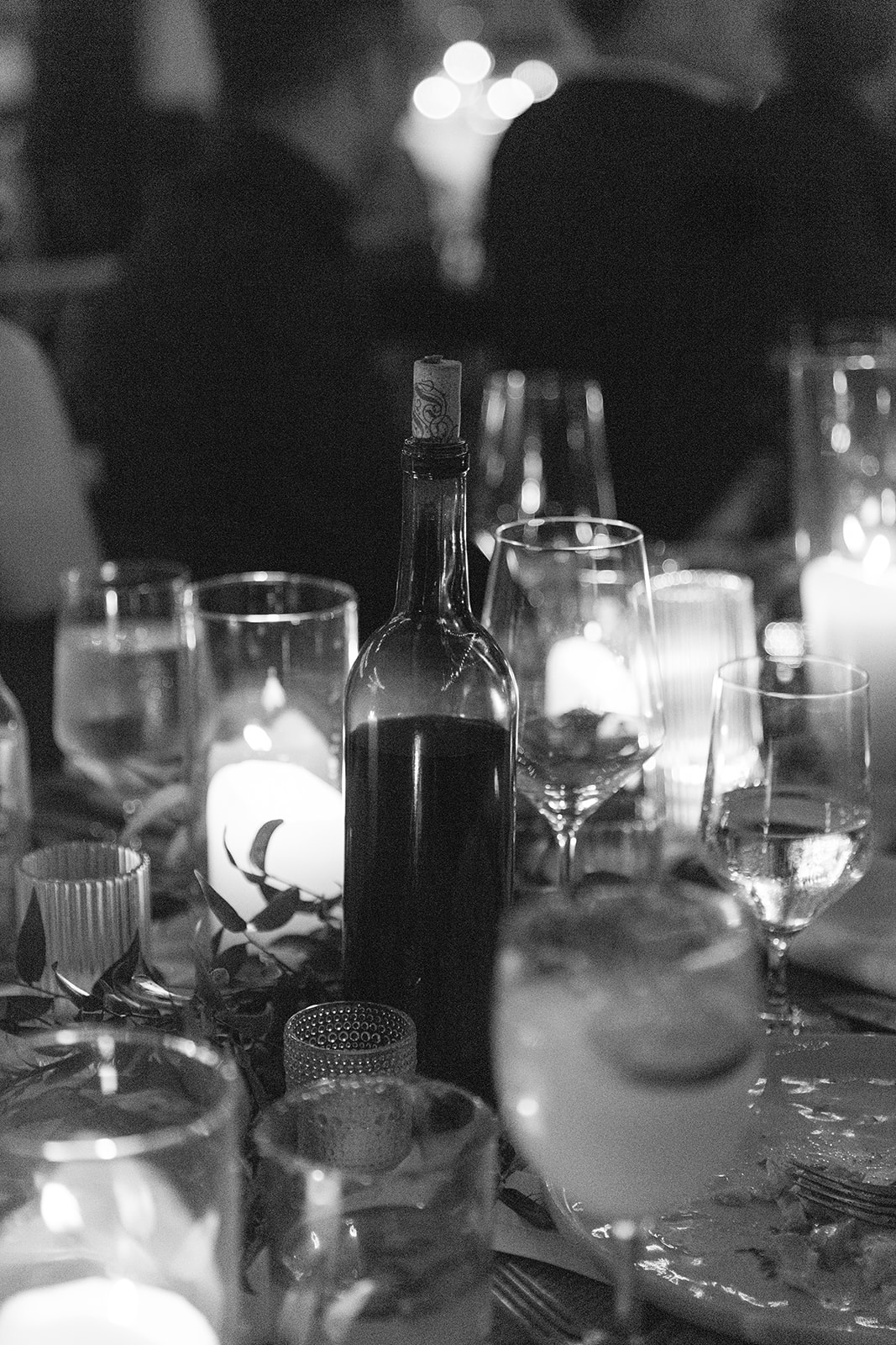 Black-and-white detail of candles, wine, and glassware at the reception.