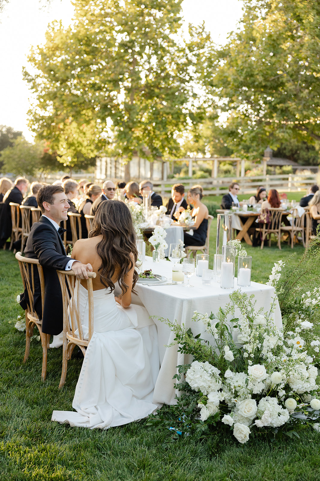 Jake and Zoe at their sweetheart table facing the outdoor reception.