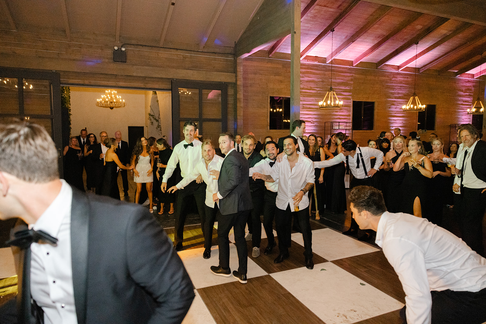 Wedding guests dancing inside the warmly lit reception space.