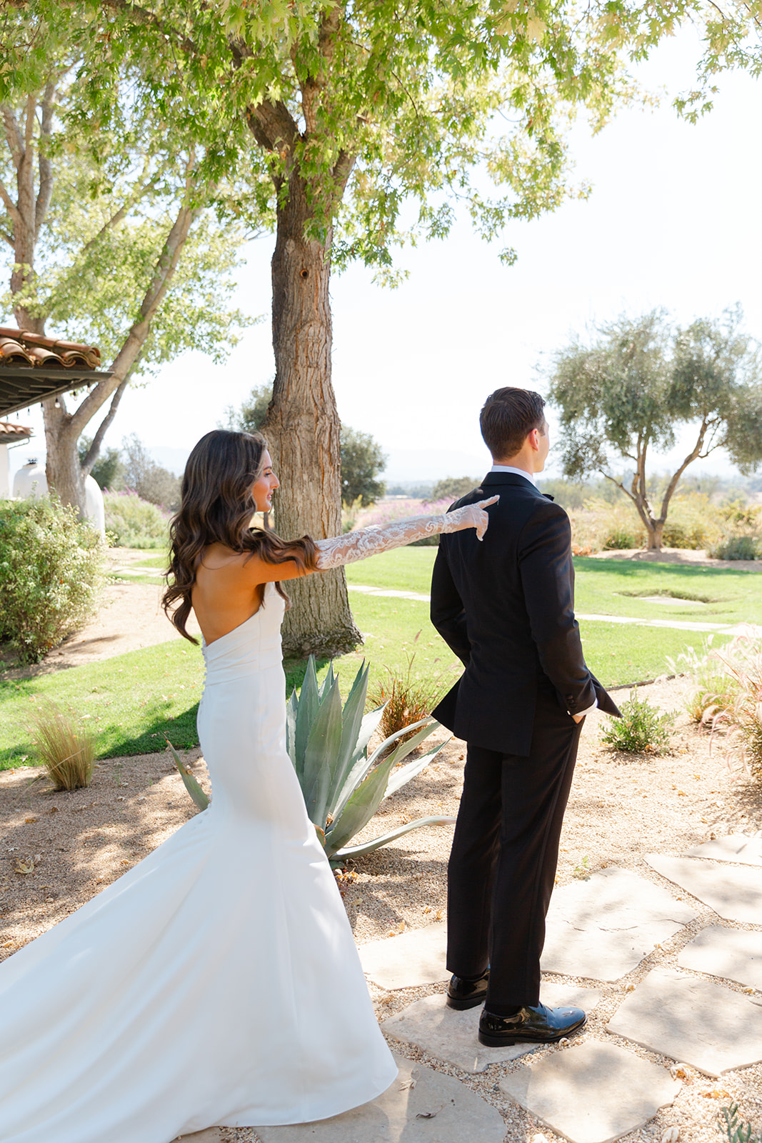 Zoe reaching toward Jake’s shoulder for their outdoor first look.