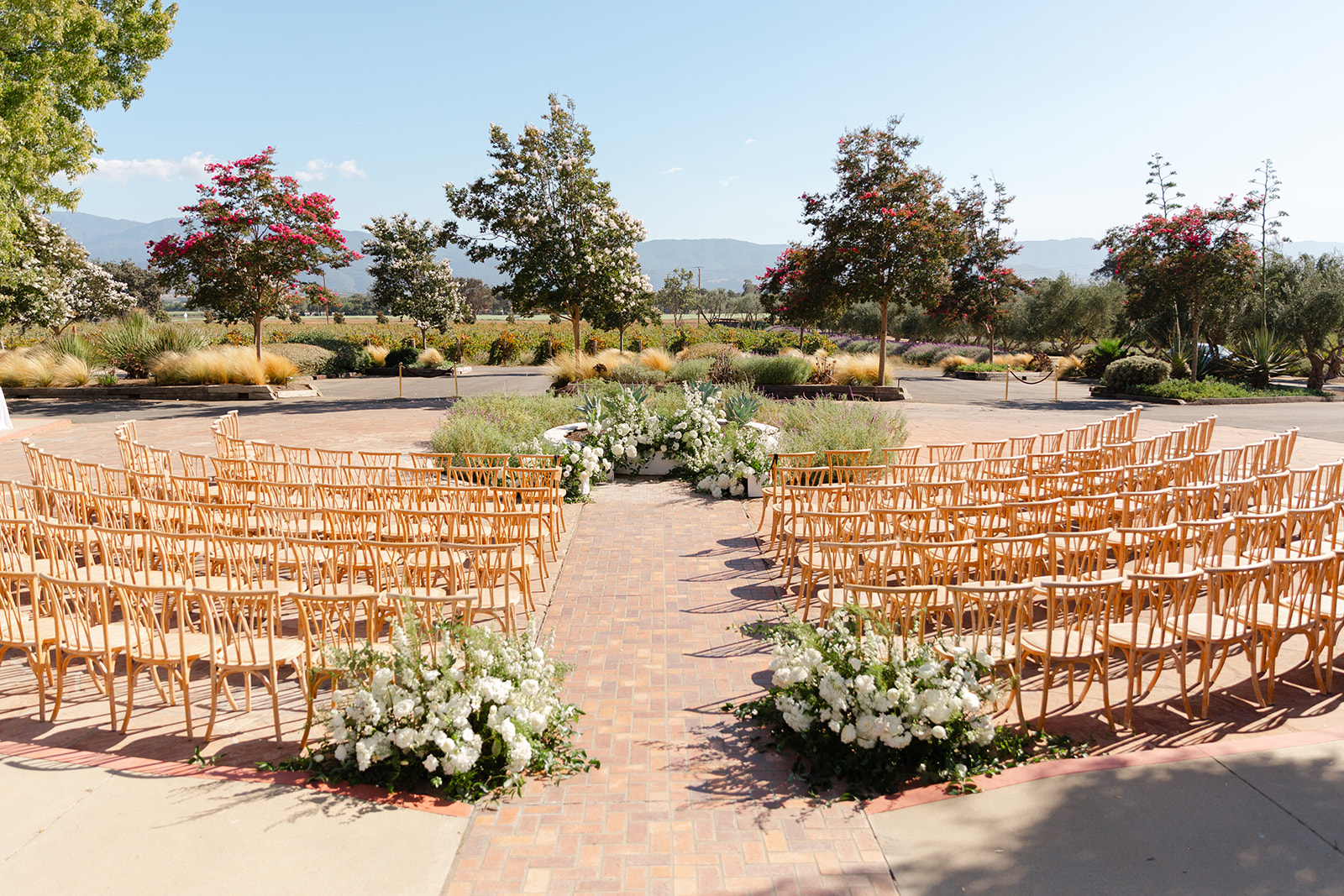 Outdoor wedding ceremony chairs and white aisle flowers with the hills beyond.
