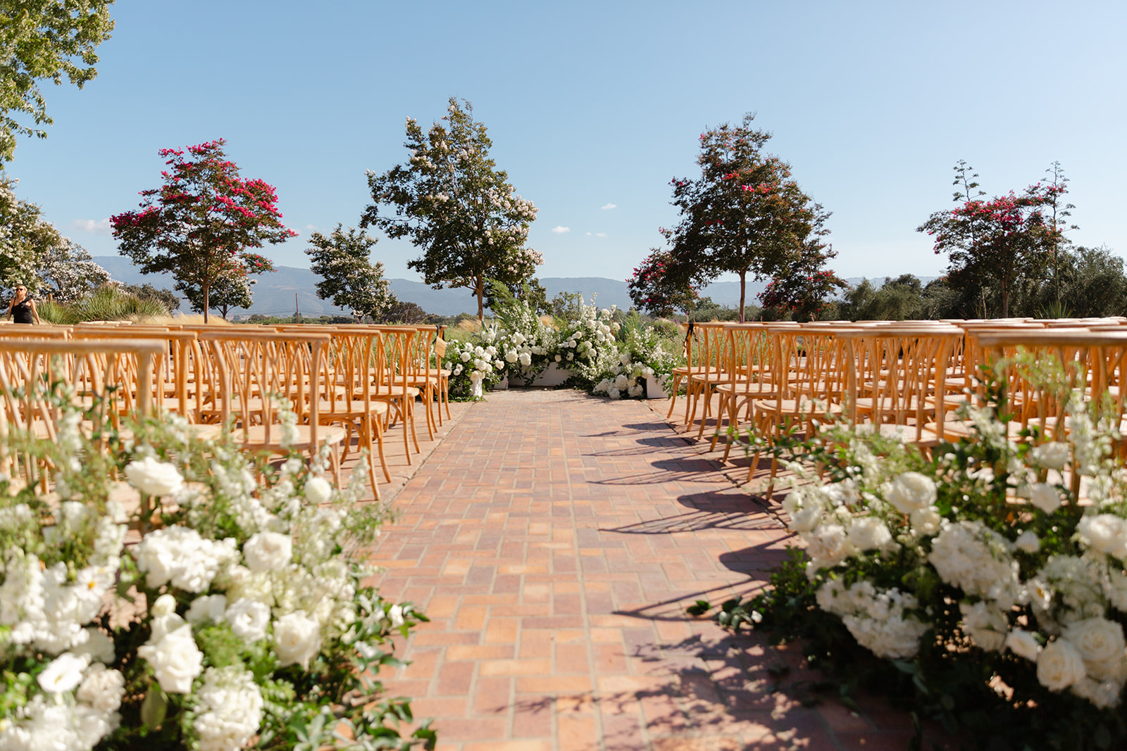 White flowers framing the entrance to the outdoor ceremony aisle.