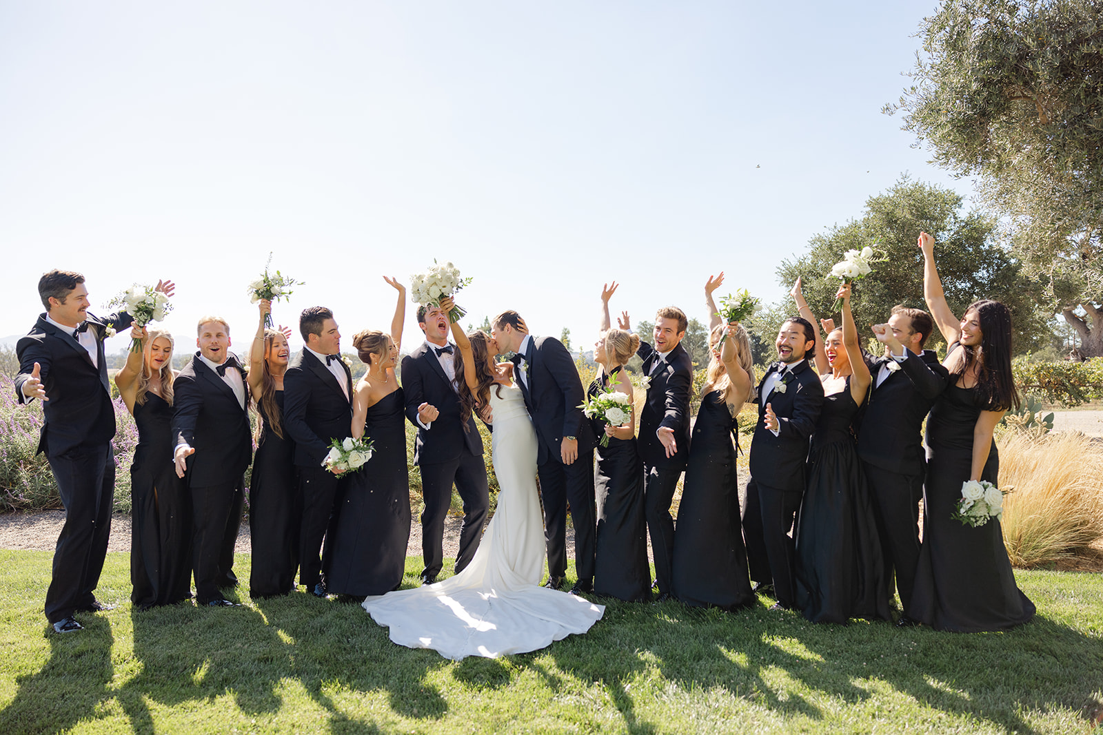 The wedding party cheering with Jake and Zoe on the lawn.