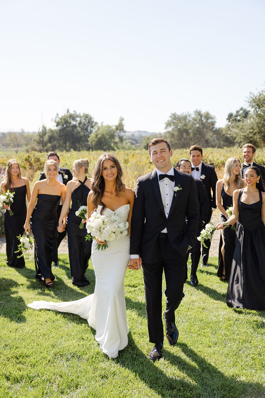 Jake and Zoe walking with their wedding party behind them.