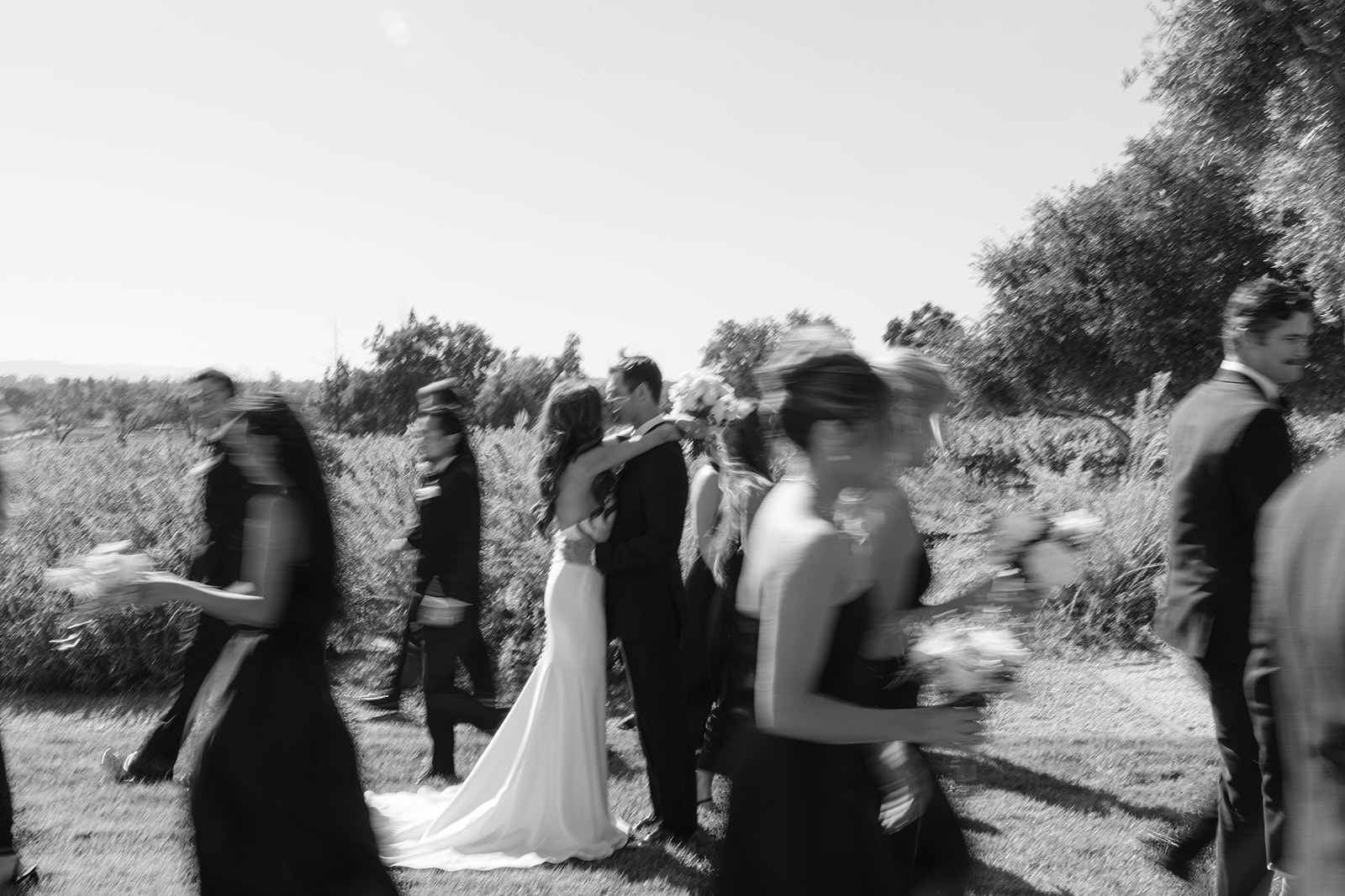 A candid black-and-white photograph of the wedding party walking together.
