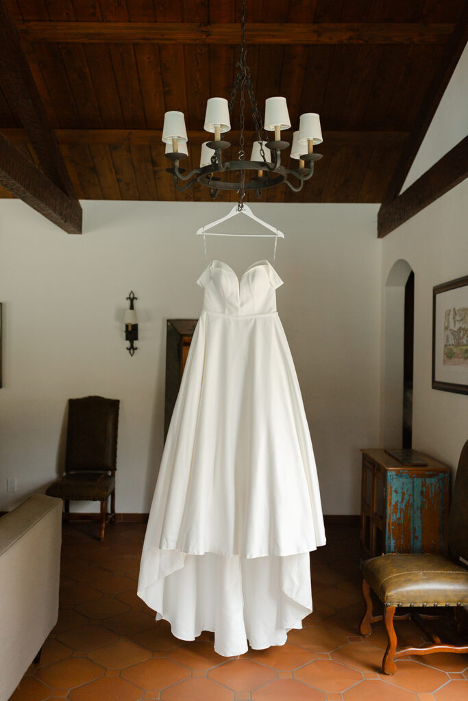 Samantha’s Essense of Australia wedding dress hanging beneath a chandelier.