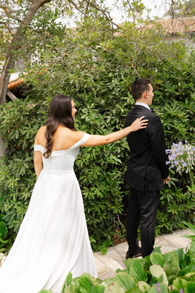 Samantha touching Andrew’s shoulder during their garden first look.