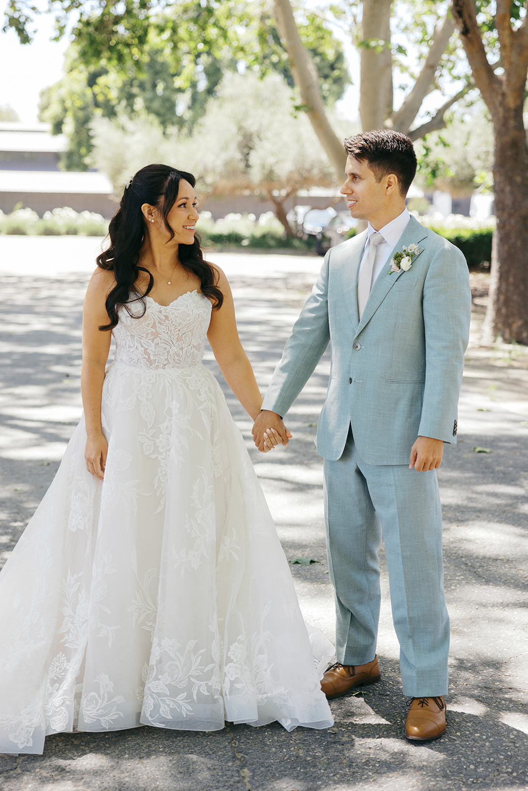 Rachel and Damien holding hands along the tree-lined drive