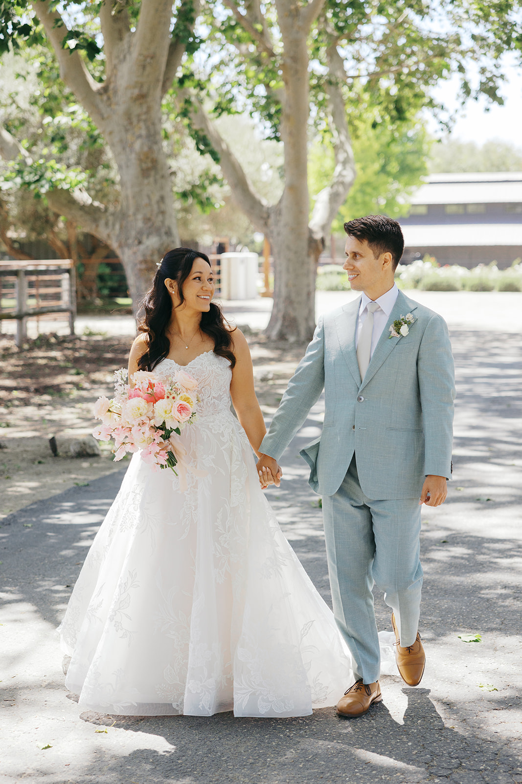 Rachel and Damien walking hand in hand beneath the trees