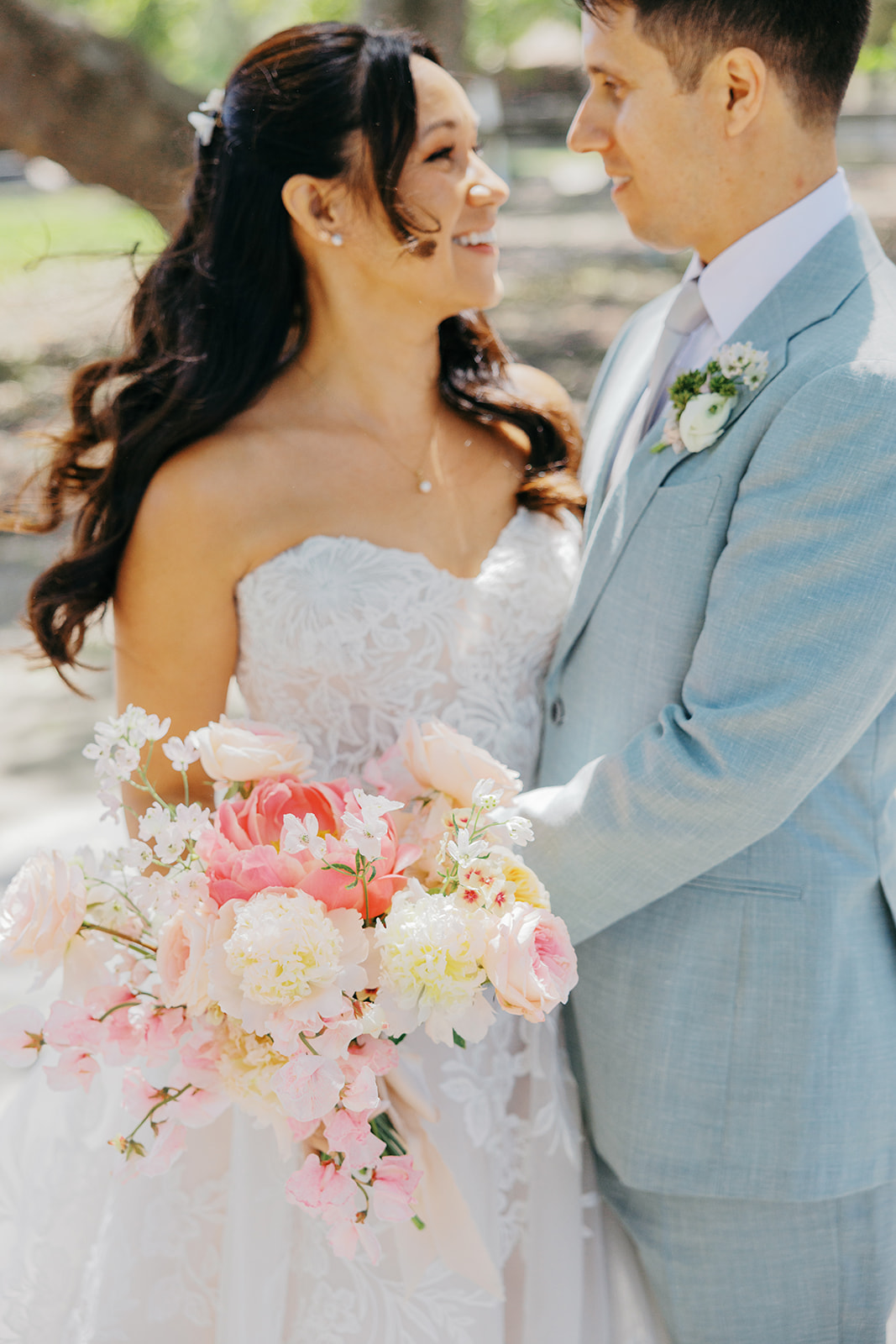 Peach bridal bouquet against Rachel’s lace gown and Damien’s suit