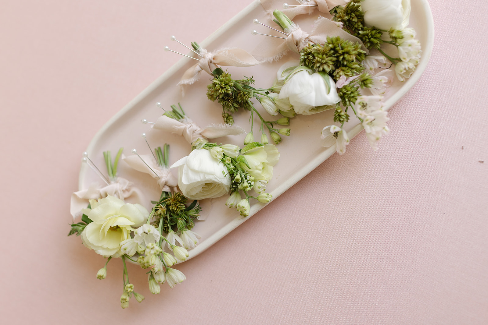 White floral boutonnieres arranged on a tray