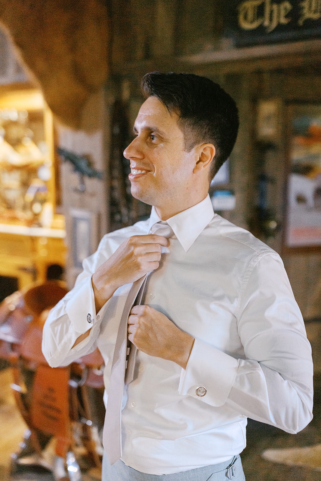Damien smiling while adjusting his tie