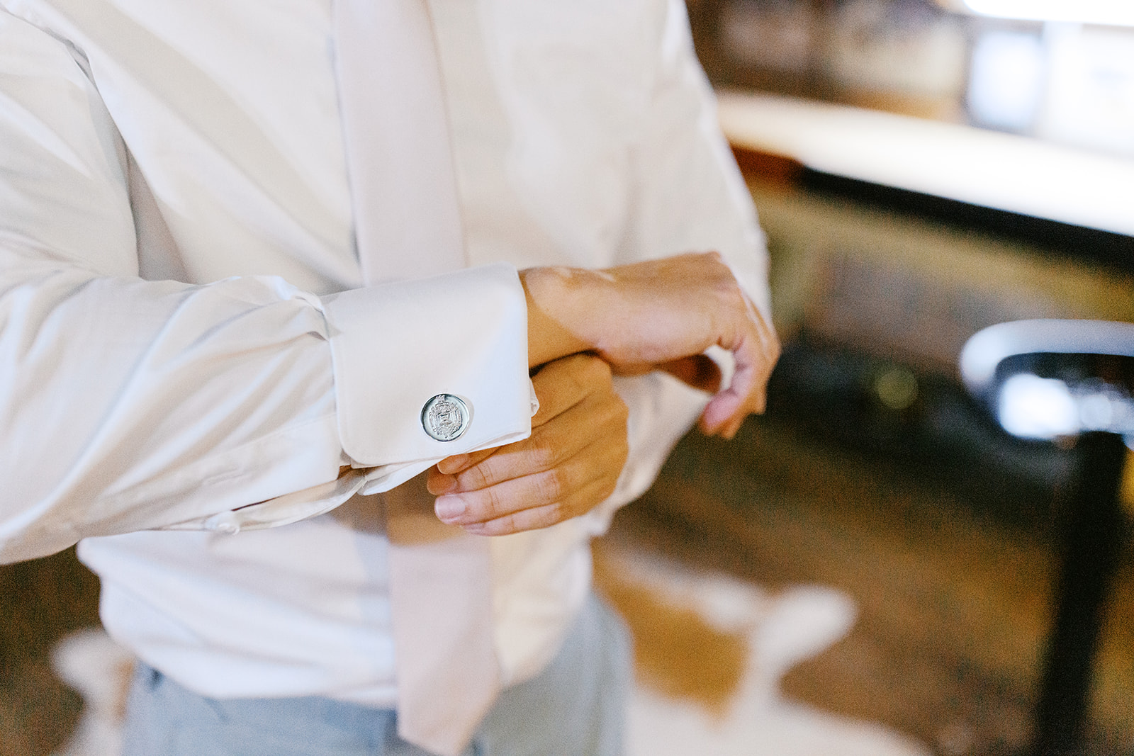Close-up of Damien fastening his cufflinks