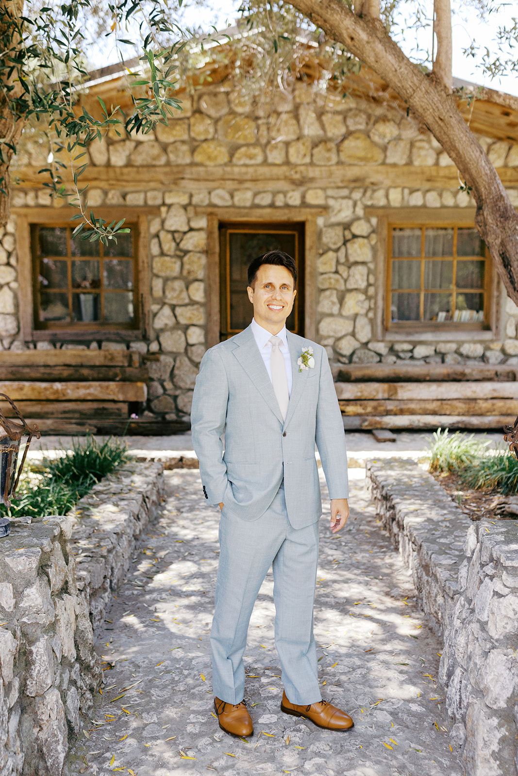 Damien in his pale blue suit outside the stone cottage