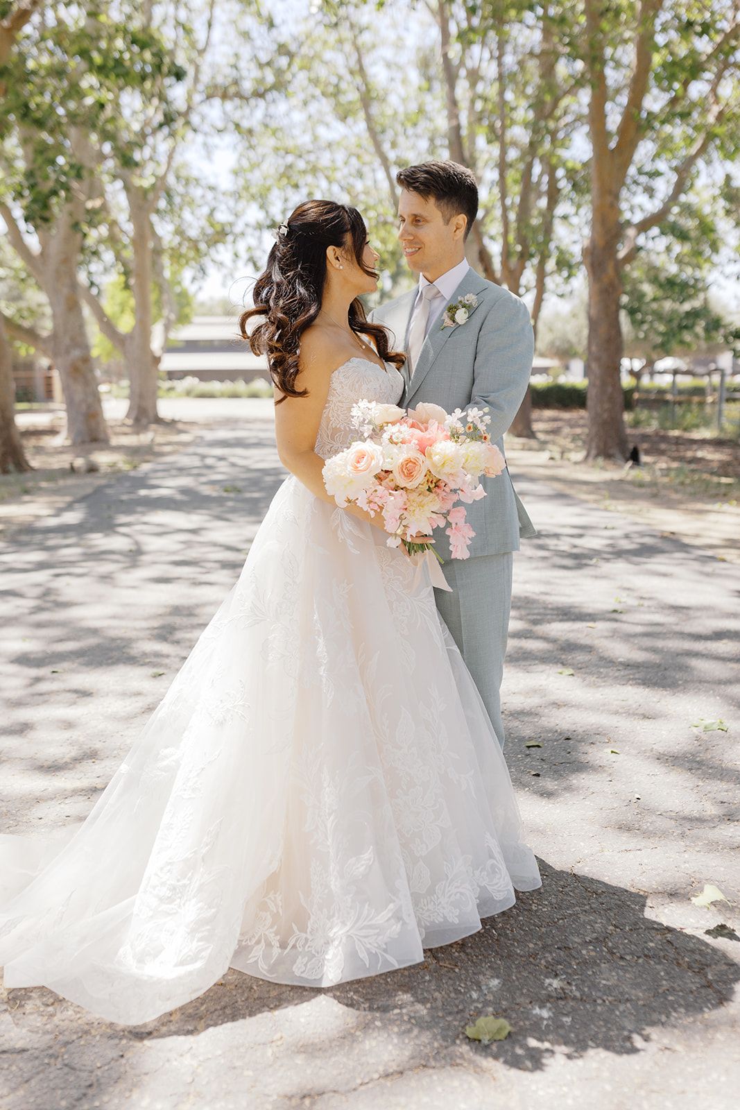 Rachel and Damien holding their bouquet beneath the trees
