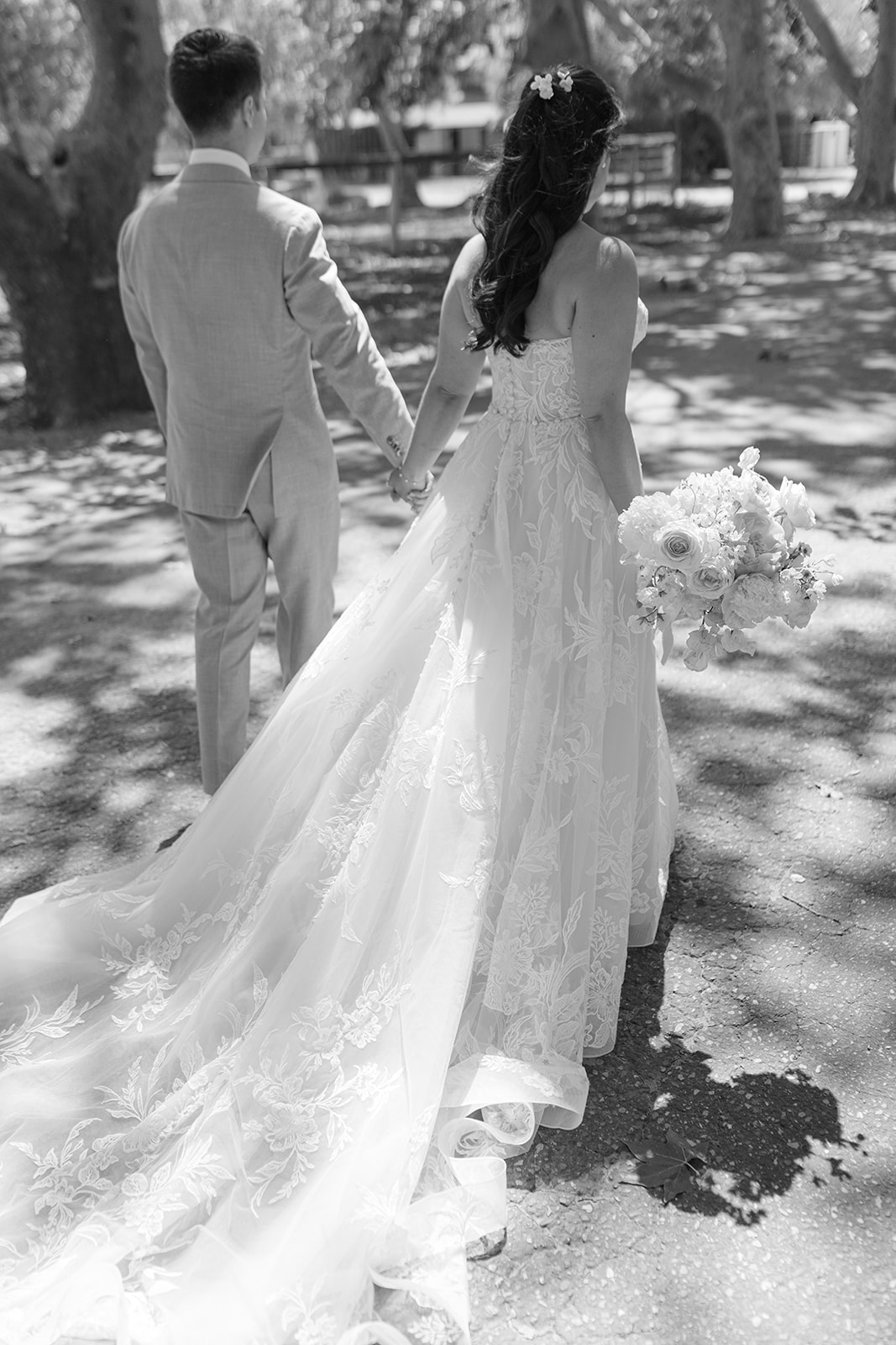 Black-and-white portrait of the couple walking beneath the trees