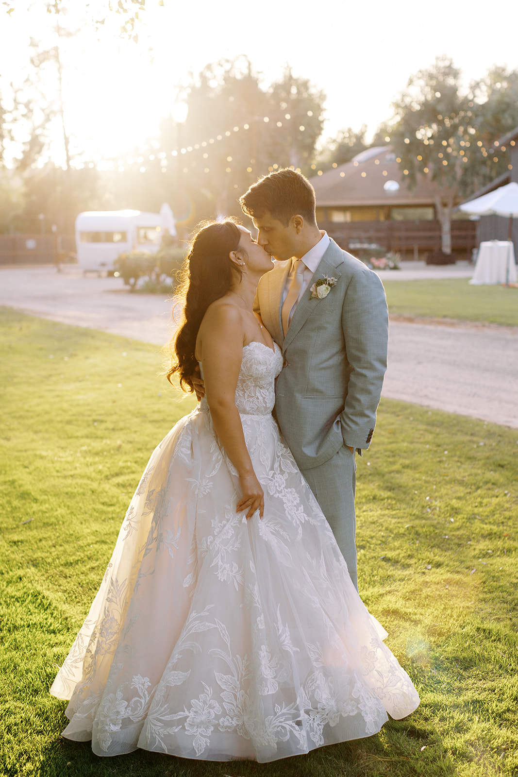 Rachel and Damien kissing on the lawn at golden hour
