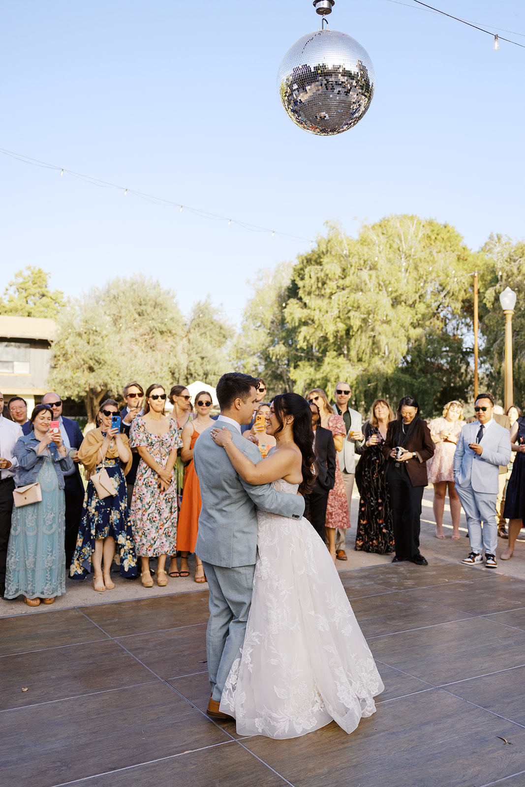 First dance beneath a disco ball and outdoor string lights