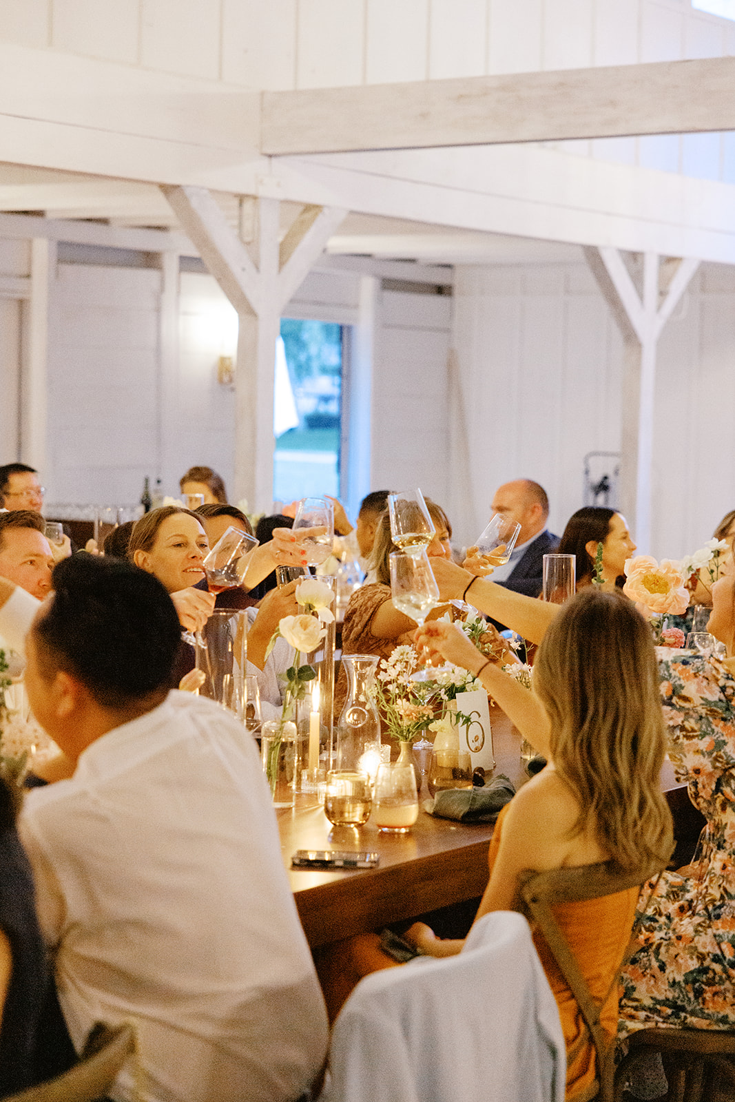 Wedding guests raising their glasses at the barn reception