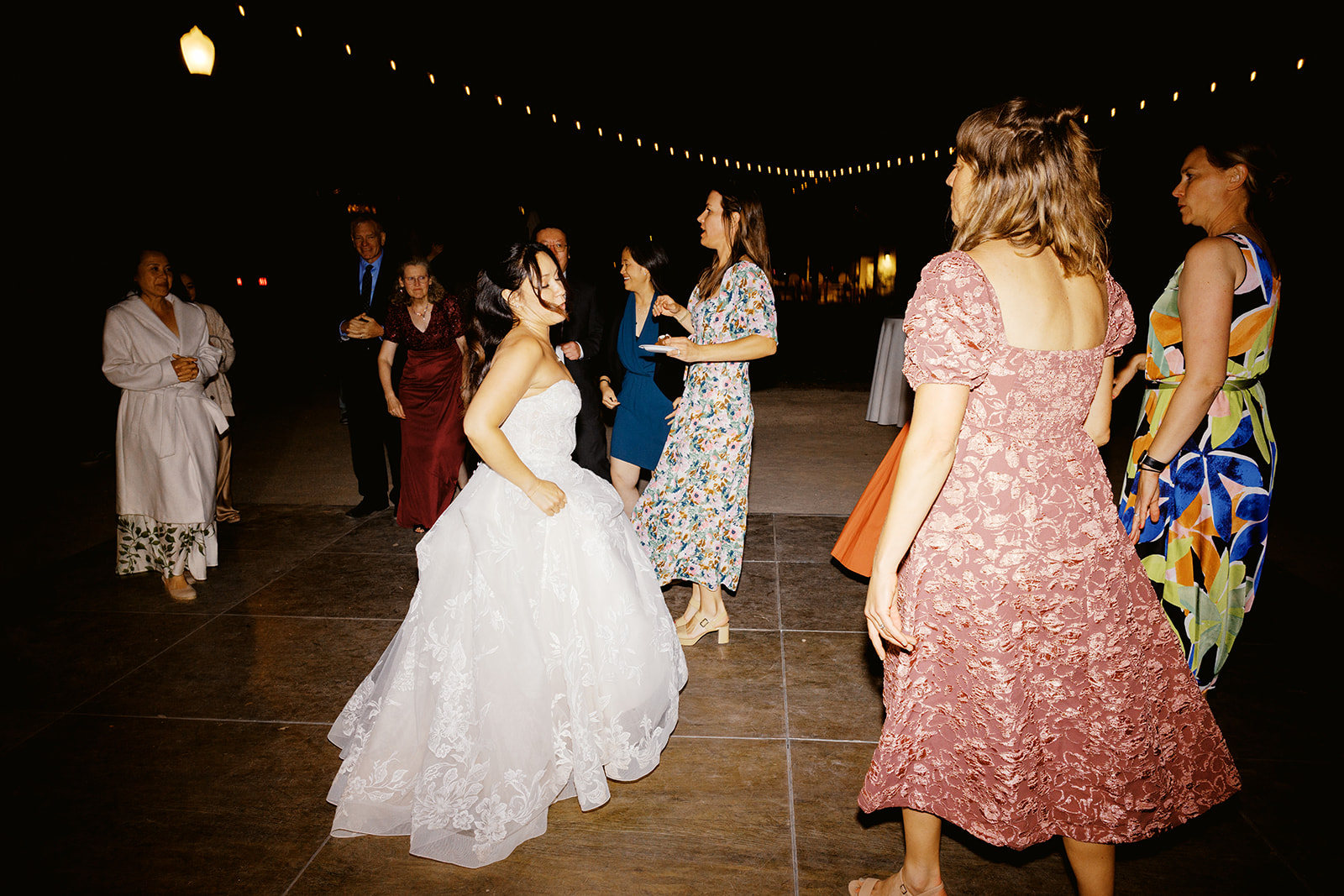 Rachel dancing with guests beneath the string lights