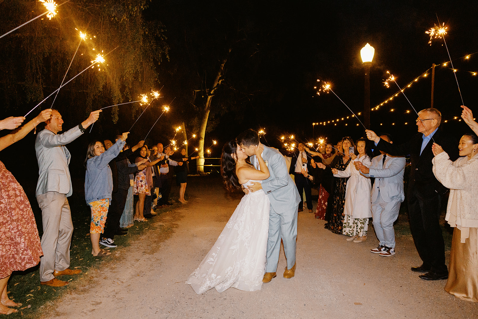 Rachel and Damien kissing beneath their guests’ sparklers