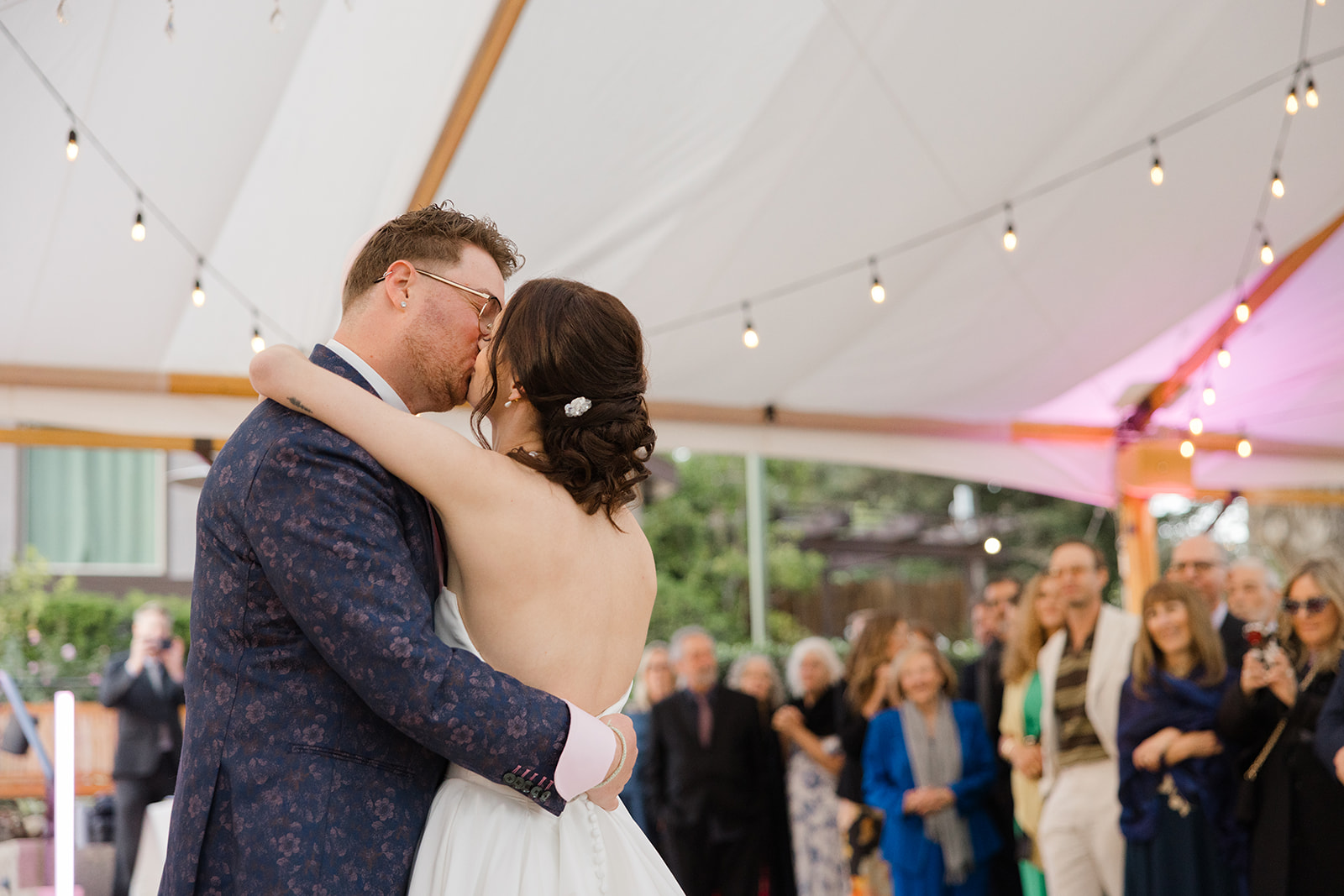 Jordan and Sara kissing beneath the reception string lights