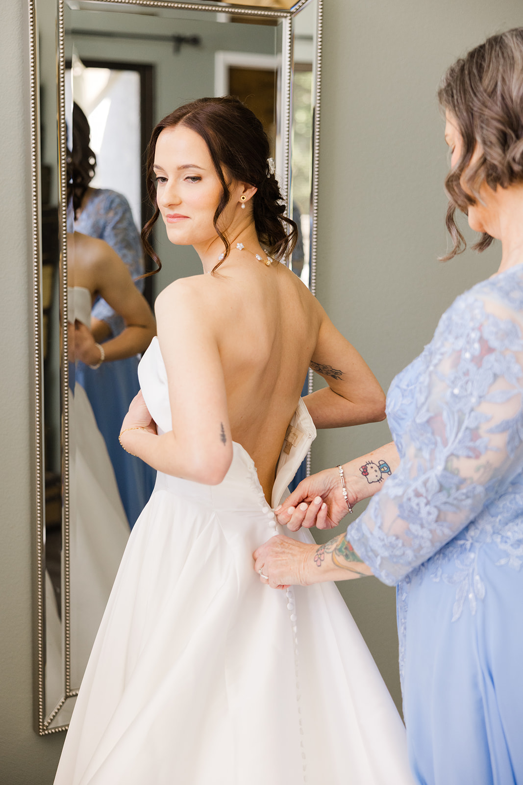 Sara’s dress being fastened before the wedding