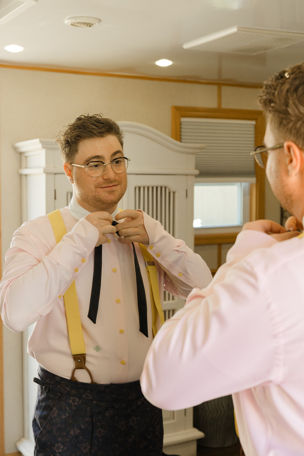 Jordan adjusting his black ribbon tie in the mirror
