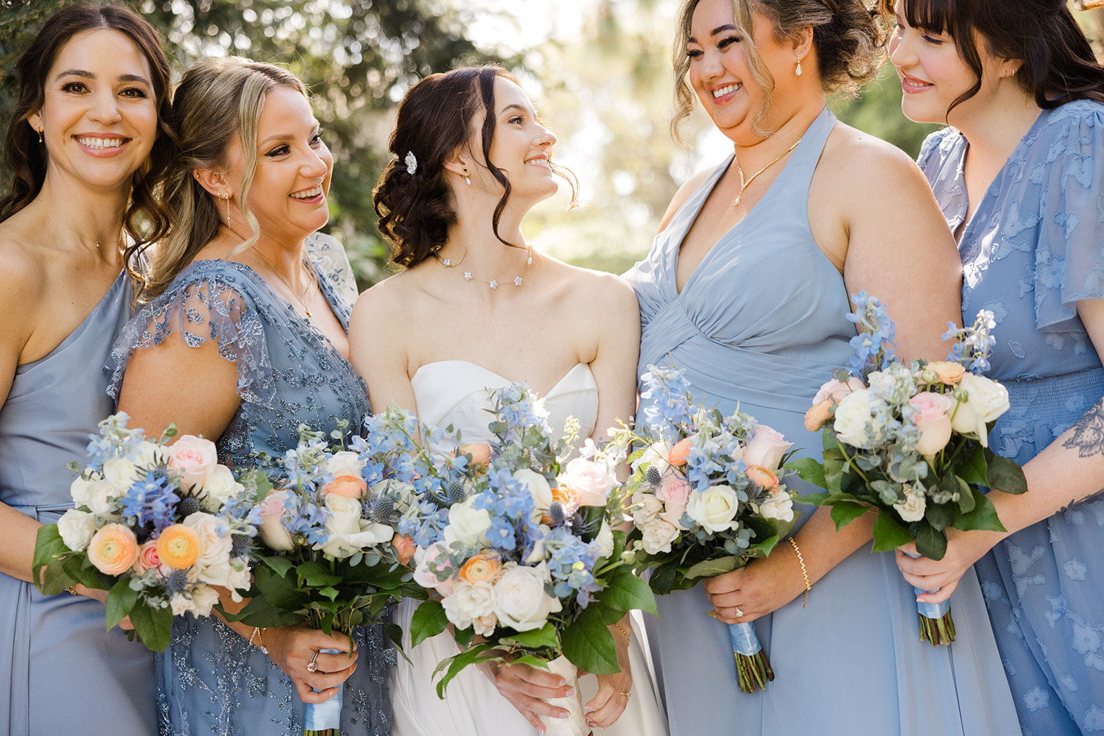 Sara laughing with her bridesmaids in dusty blue dresses