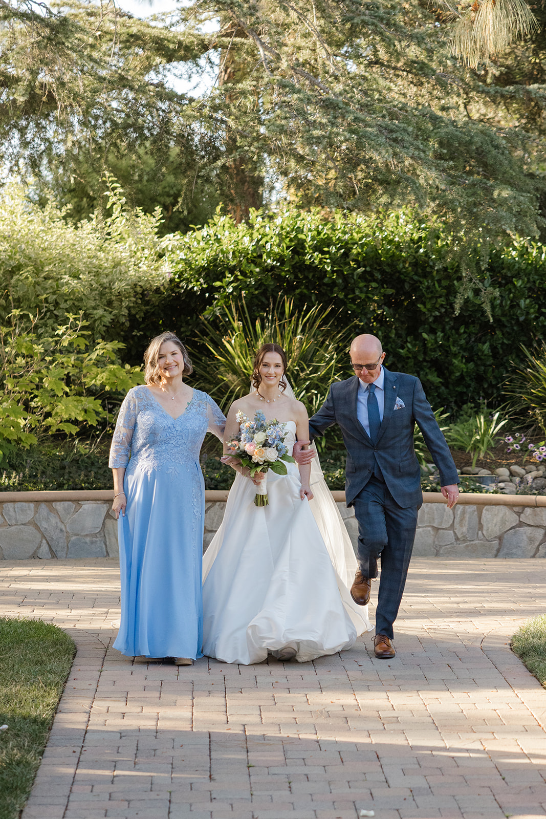Sara walking down the garden aisle with her parents