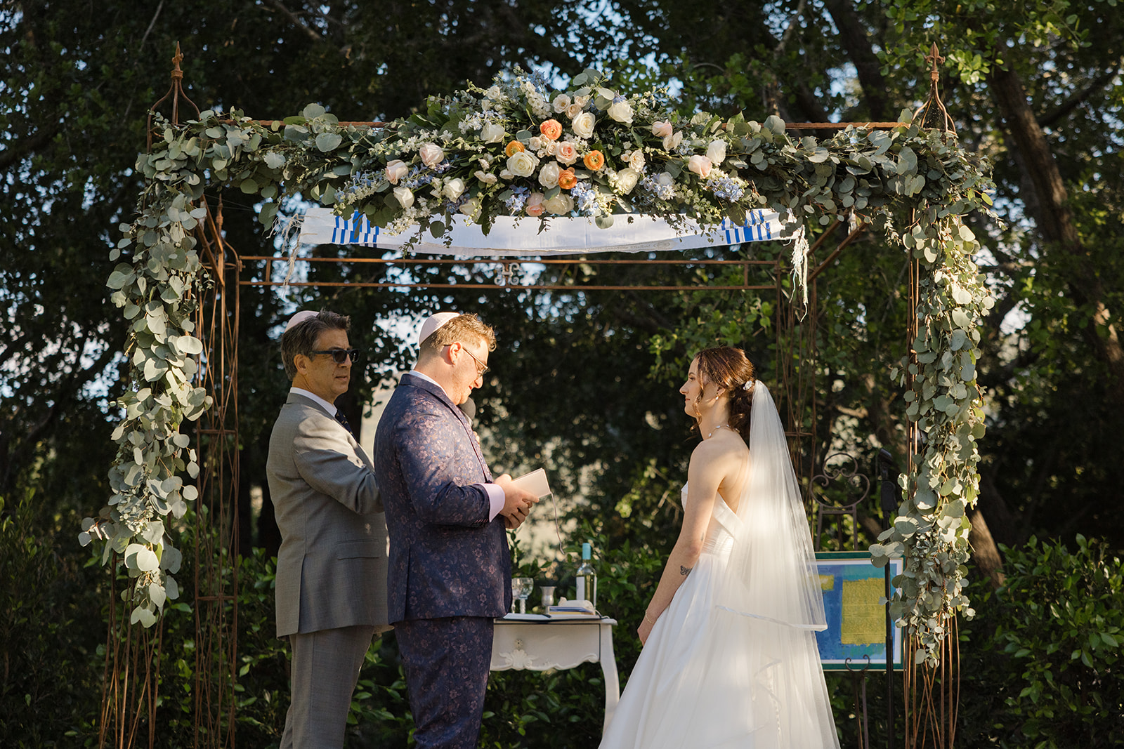 Jordan reading his vows beneath the floral chuppah