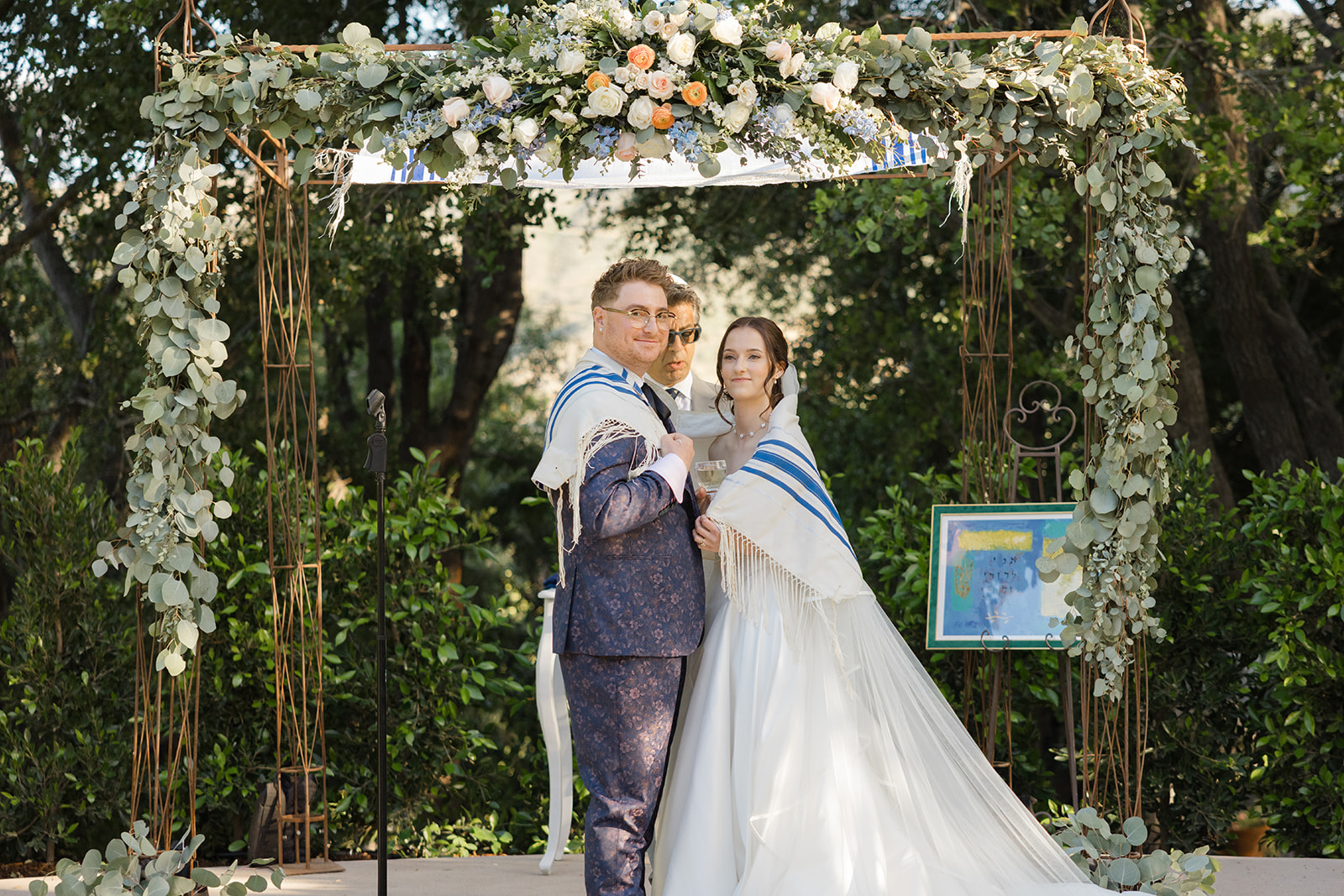 Jordan and Sara wrapped together in a tallit beneath the chuppah