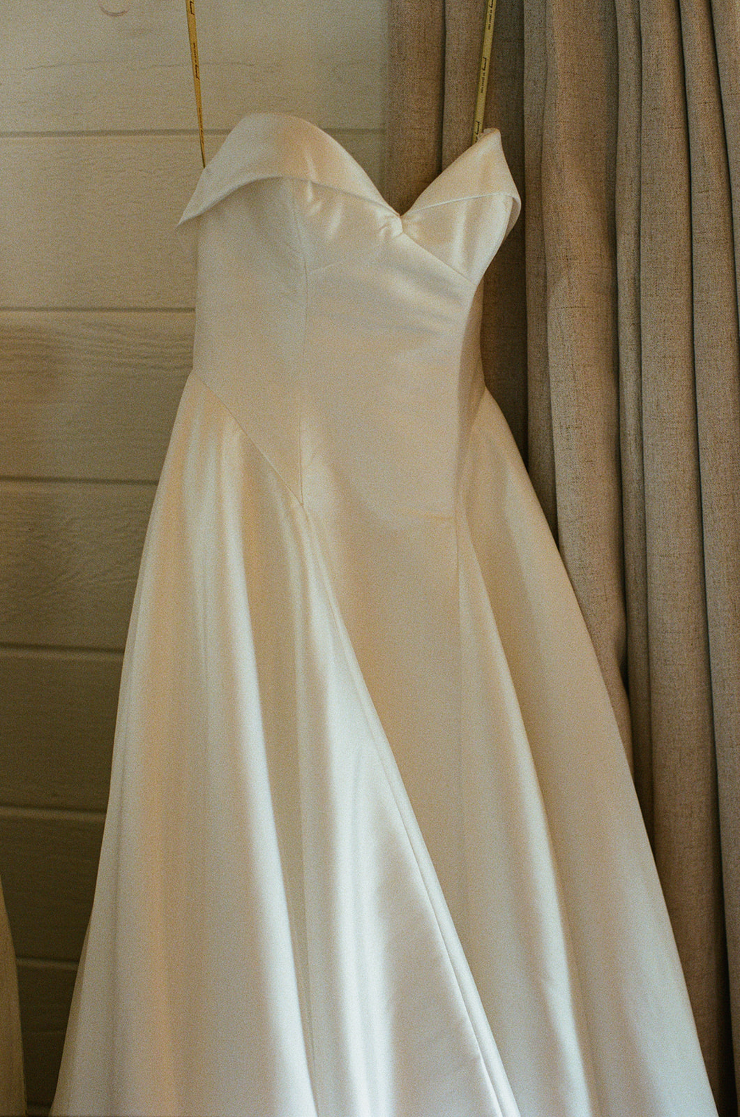 Film photograph of Sara’s strapless gown hanging by the window