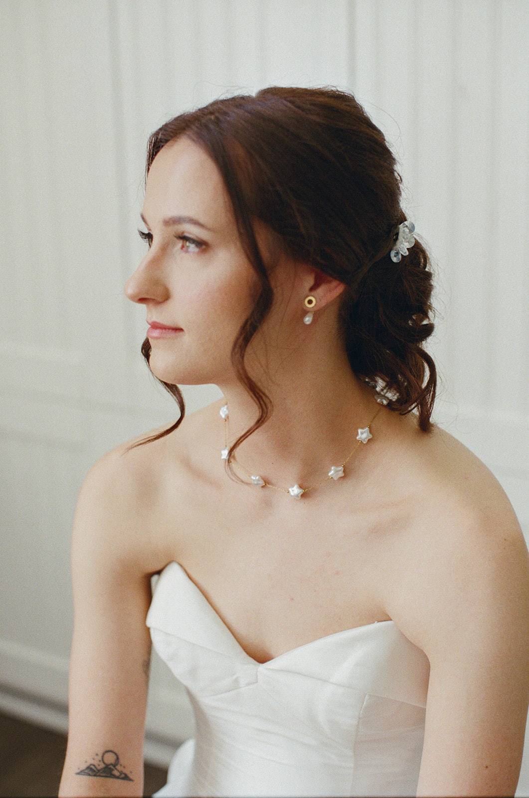 Film portrait of Sara’s softly curled updo and floral jewelry