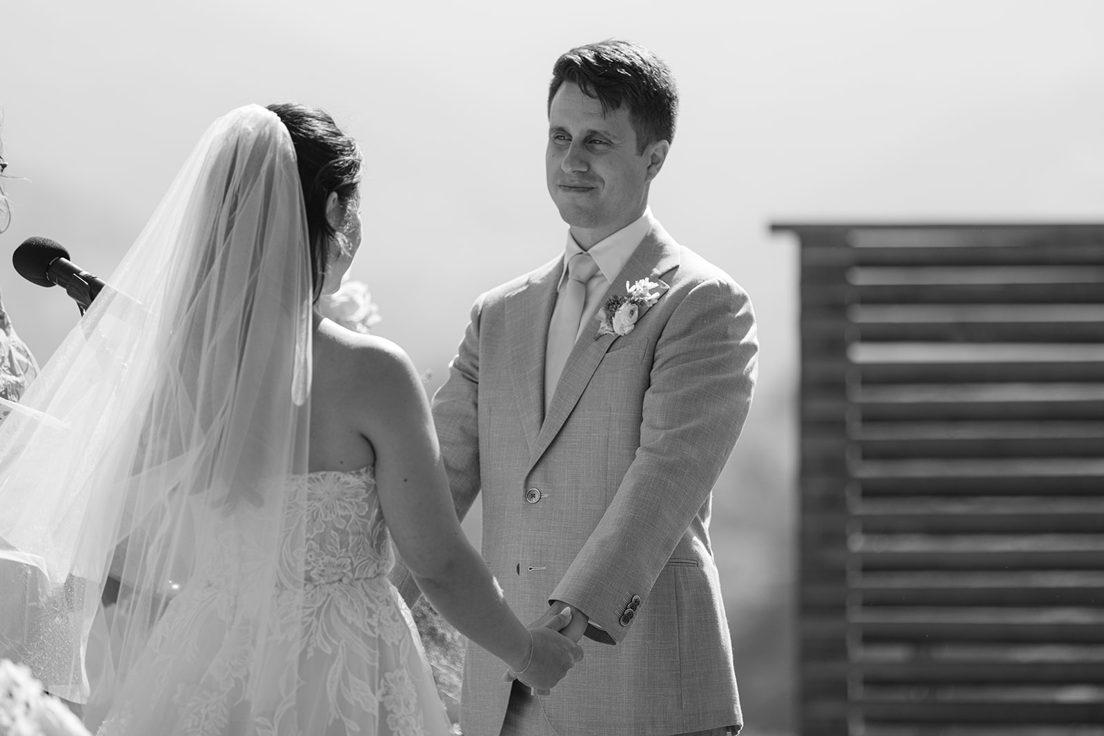 Black-and-white photograph of Rachel and Damien holding hands during the ceremony